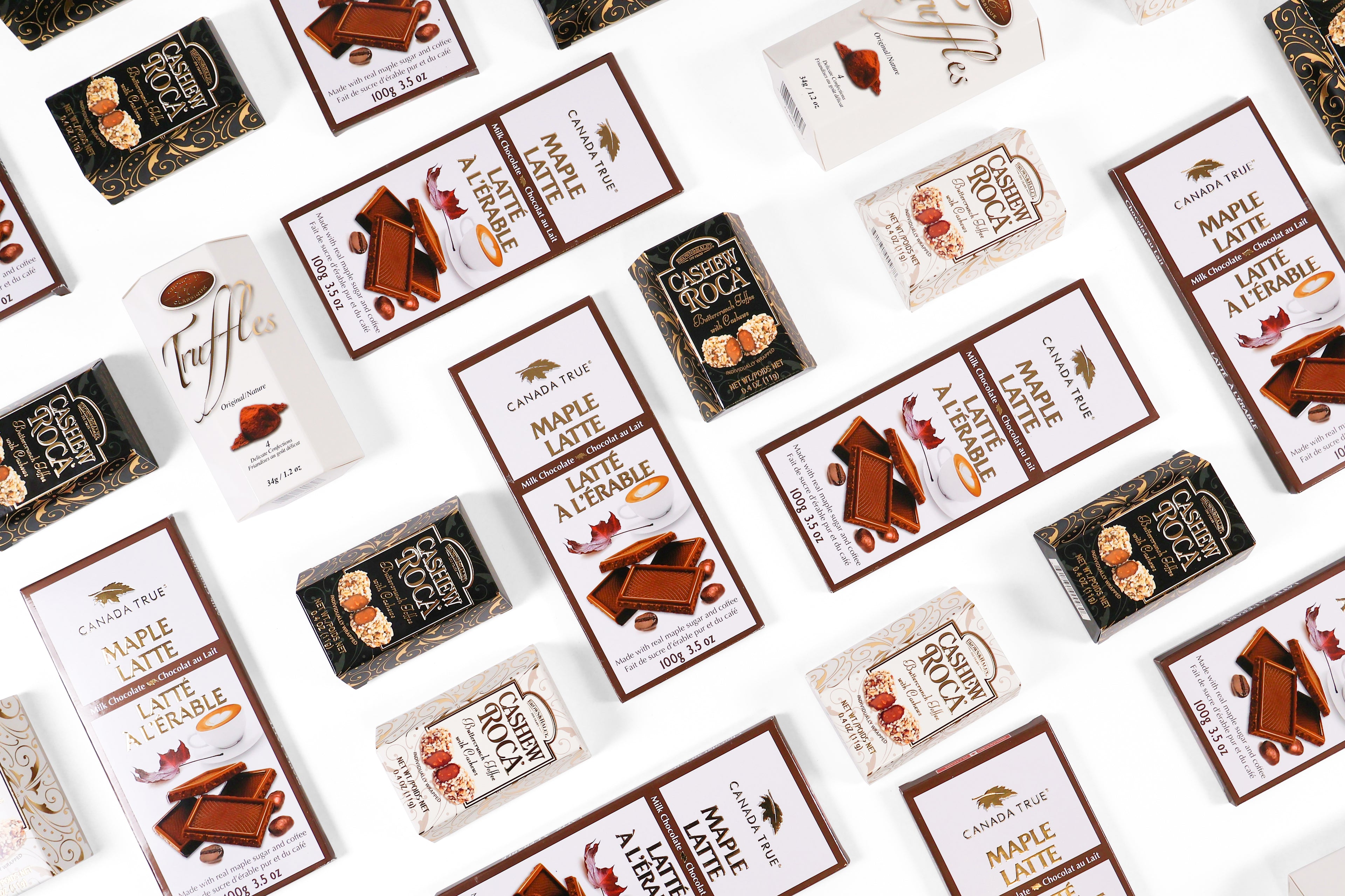 An assortment of chocolate treats, including Cashew Roca and Maple Latte bars, beautifully arranged on a white background.