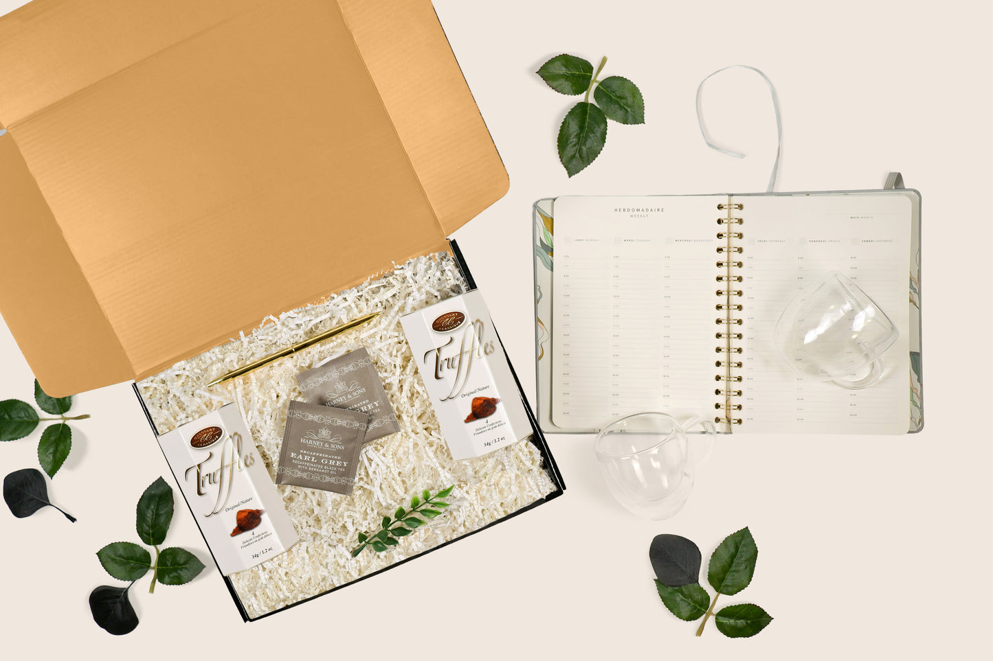 Unboxed productivity gift set featuring planner, mugs, truffles, tea, and pen arranged with filler and greenery in a kraft gift box.