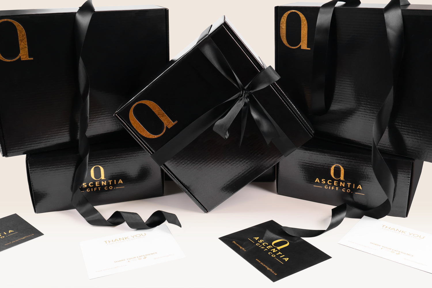 Three elegant black gift boxes with gold detailing, tied with black ribbons, featuring a "Thank You" card and Ascentia Gift Co. branding.