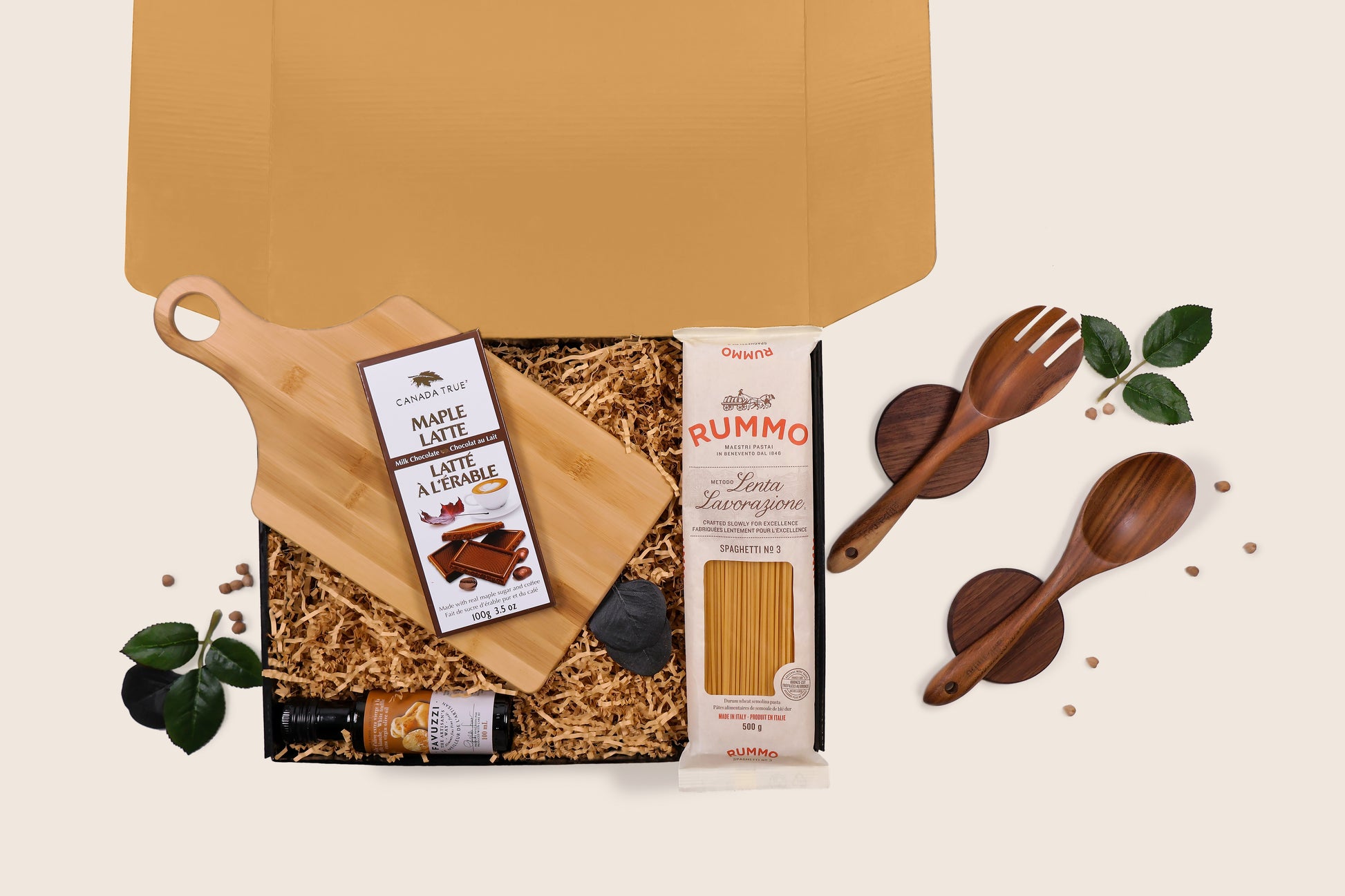 The Host’s Gourmet Essentials gift box unboxed, featuring Rummo spaghetti, maple chocolate, truffle oil, wooden utensils, and bamboo board in kraft packaging.